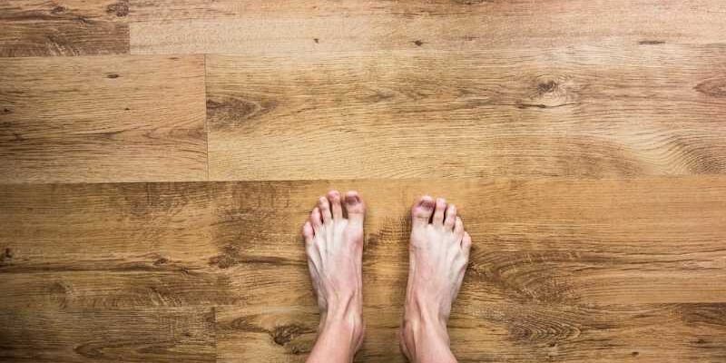 ein paar nackte Füße, die auf einem Parkett stehen