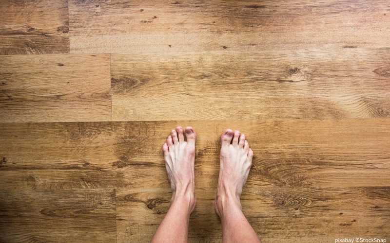 ein paar nackte Füße, die auf einem Parkett stehen
